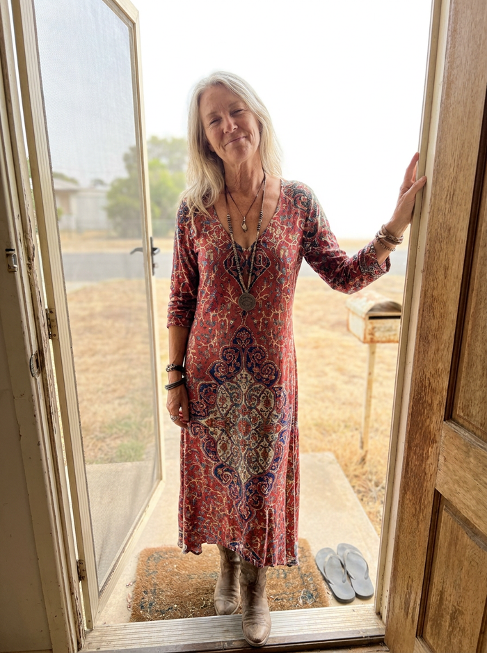 Woman wearing the Olivia draped dress in a front doorway